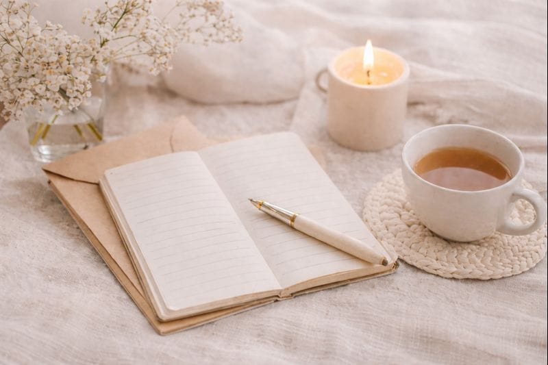 Ambiance chaleureuse avec carnet, thé et bougie, symbole de douceur et de partage chez Maison Althee